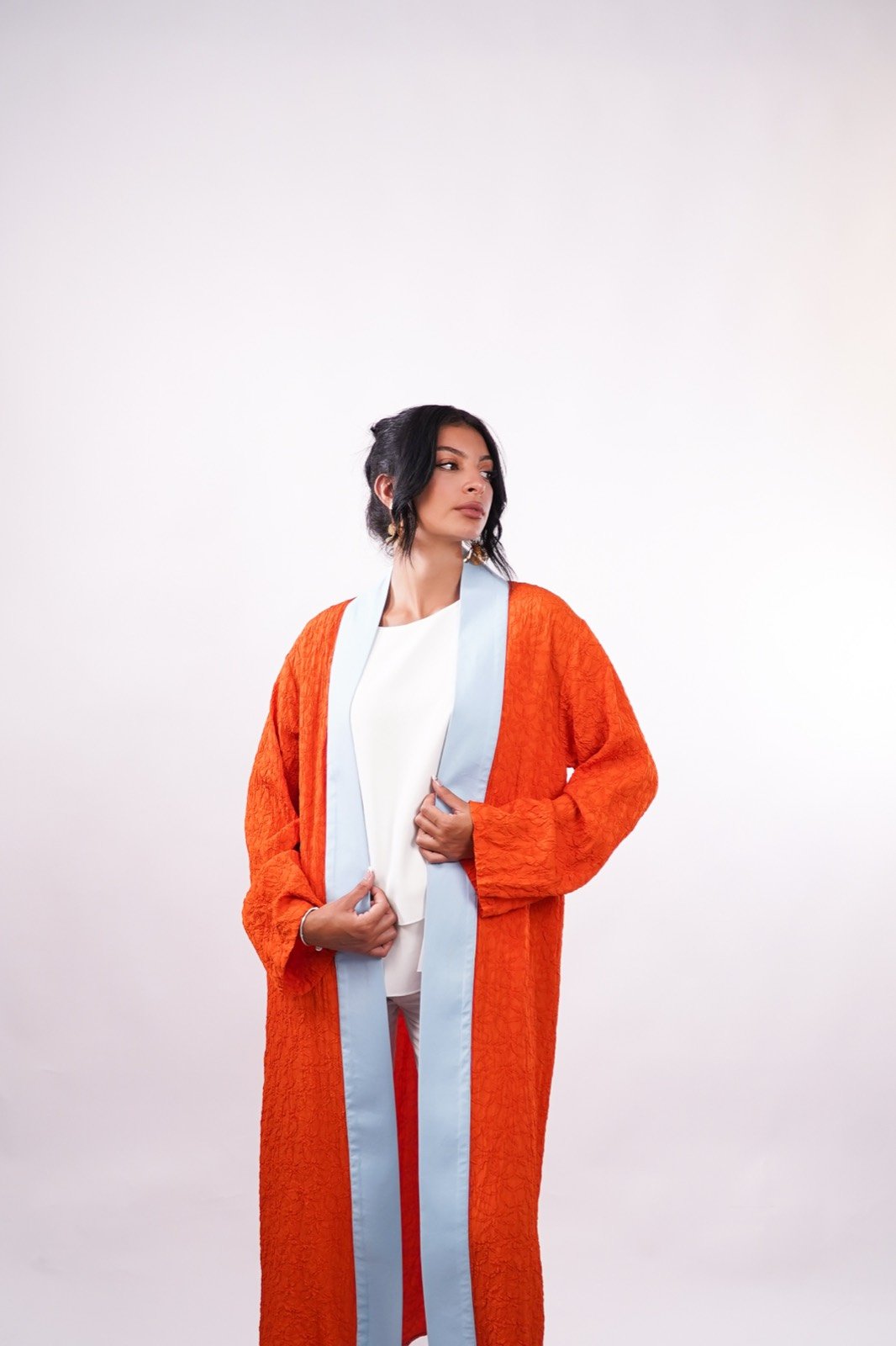 Amber Sky open-front robe in burnt orange, standing, robe open over wide trousers, from the Le Kanz summer collection