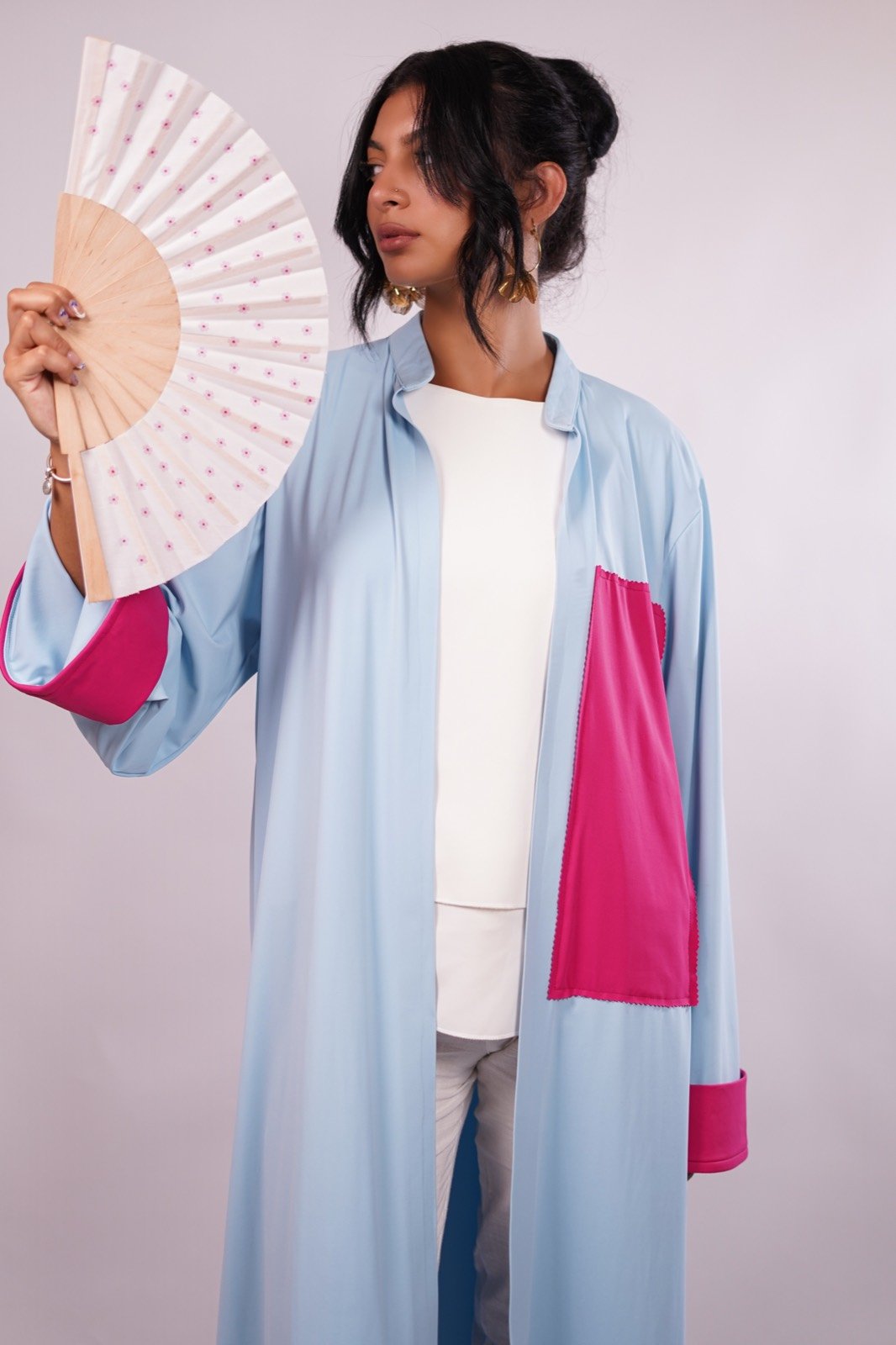 Hydrangea open-front robe in pale blue with fuchsia cuffs, held open beside a folding fan, from the Le Kanz summer collection