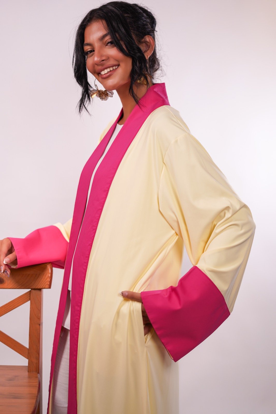 Rose Soleil open-front robe in cream with fuchsia trim, seated, sleeve draped forward, from the Le Kanz summer collection